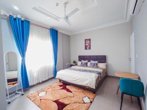 - une chambre avec un lit doté de rideaux bleus et d'un tapis dans l'établissement Kings View Apartment, à Achimota