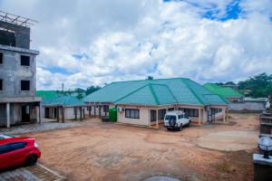 MzuzuCloud9 Hotels and Resorts的位于泥地上的绿色屋顶建筑