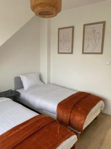 due letti in una stanza con pareti bianche di La maison de Julien a Bourbourg