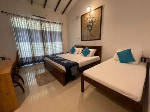 a bedroom with two beds and a desk and window at Coral Breeze Hikkaduwa in Hikkaduwa +12 photos