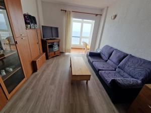 a living room with a purple couch and a tv at Disfruta el mar in Bajamar
