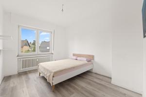 a white bedroom with a bed and a window at Geräumiges Familienhaus Köln in Niederdorla
