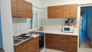 a kitchen with wooden cabinets and a sink and a microwave at Beach Apartments Luka in Tribanj-Krušćica