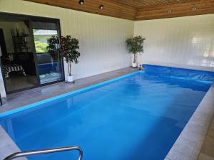a large swimming pool with blue water at Ferienhaus Petzenblick - ganzjährig beheizter und privater Indoorpool in Konovece