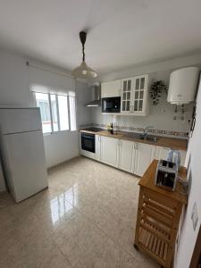 Una cocina con gabinetes blancos y un refrigerador blanco. en Violeta del Teide, en Icod de los Vinos