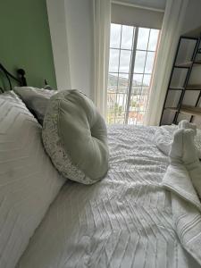 Cama blanca con almohada y ventana en Violeta del Teide, en Icod de los Vinos