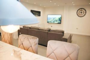 a living room with a couch and a clock on the wall at 5BDR Spacious En-suite Accomodation in Coventry