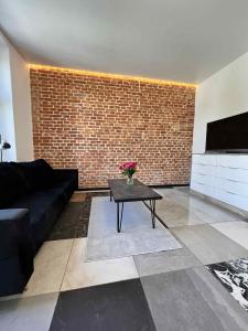 Una sala de estar con un sofá negro y una mesa. en Dworskiego 74 Apartament 5, en Przemyśl