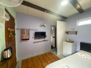a bedroom with a bed and a tv on the wall at Merdeka Guest House 2 in Kuching