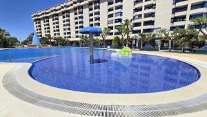 an empty swimming pool with an umbrella in front of a building at BEACH VALENCIA LUXURY D15-21 Apartment with terrace and sea views with two rooms in Valencia
