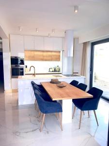 a kitchen with a wooden table and blue chairs at Luxury beachfront apartment with private pool, Vinjerac in Vinjerac