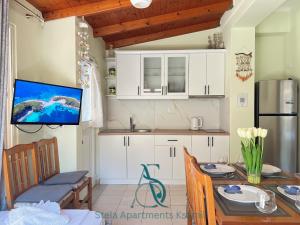 a kitchen with white cabinets and a table with a television at Stela Apartments in Ksamil