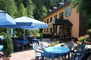 an outdoor patio with tables and chairs and umbrellas at Waldhotel Albachmühle mit Albacher Stuben in Wasserliesch