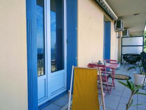 un porche con puerta azul, mesa y sillas en Appartement familial - Vue mer, en Bastia