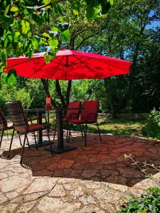a table and chairs with a red umbrella at Petra's House in Komaji