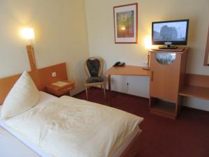 a hotel room with a bed and a desk with a television at Hotel Rose in Georgsmarienhütte
