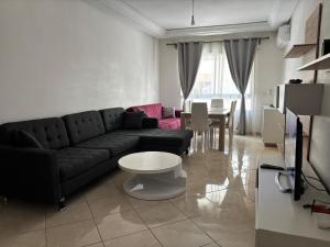a living room with a black couch and a table at Magnifique Appartement Inès complexe Aida village in Tangier