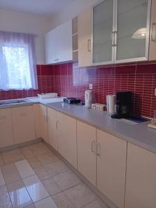 an empty kitchen with white cabinets and red tiles at Cozy flat in Nea Makri in Nea Makri