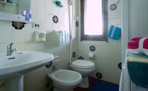 a white bathroom with a sink and a toilet at Villetta con terrazza a 400 mt dal mare in Geremèas