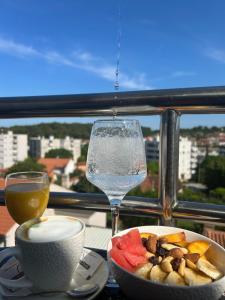 a table with a glass of wine and a bowl of fruit and a plate at Artena Hotel in Pula