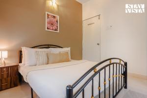 a bedroom with a bed with white sheets and pillows at Belas Palmeiras by VEO - Part of StayVista with Pool & Bonfire in Alibaug