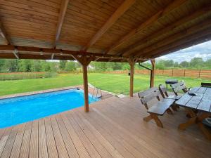 a wooden deck with a picnic table and a pool at Drewniana ostoja, jacuzzi, sauna, basen - domek na wyłączność in Jelonek
