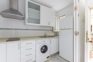a white kitchen with a washing machine and a refrigerator at Ribera del río - Centro in El Puerto de Santa María