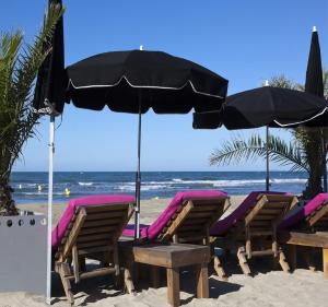 um grupo de cadeiras e um guarda-sol na praia em Vittoria Immobilier 5 - REGLEMENT SUR PLACE - chèques vacances acceptés em La Grande-Motte