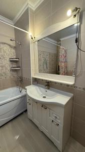 a bathroom with a sink and a mirror and a tub at #52 Просторная 3 комнатная квартира in Atyraū