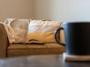 a couch with a blanket on it with a coffee mug at Modern Mountain Oasis Top floor 2 level 2bd in Canmore