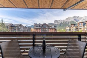 a table and chairs on a balcony with a view of mountains at Modern Mountain Oasis Top floor 2 level 2bd in Canmore
