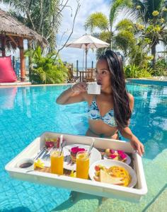 una mujer sentada en una piscina con una bandeja de comida en Panorama Ekas, en Ekas