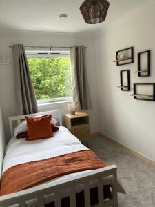 a bedroom with a bed with an orange pillow and a window at 3 Bedroom Apartment - Loch Linnhe Views - Modern & Chilled Highland Stay in Fort William +3 photos