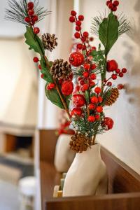 a vase filled with red berries and christmas decorations at Lovehome - 4BD Villa with views-15mins to airport,10mins to MEC ΑΕ- 2mins to bus stop ,10mins to Suburban Railway on foot in Athens