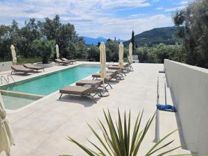 a swimming pool with lounge chairs and umbrellas at Elpida Luxury Apartments Suites in Nydri
