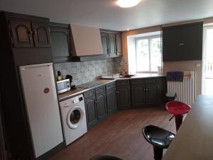 a kitchen with brown cabinets and a washer and dryer at 3 chambres pour 6 personnes in Peyrilhac