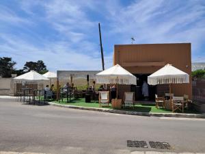 a group of people sitting at tables under umbrellas at Onde Salentine Deluxe in Casalabate