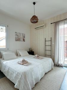 una camera da letto bianca con un grande letto con asciugamani sopra di Lefkada City Escape a Città di Lefkada
