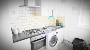 a kitchen with a stove and a washing machine at Canary wharf cottage in London