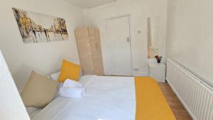 a small bedroom with a white bed with yellow accents at Canary wharf cottage in London
