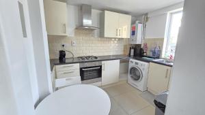 a kitchen with white cabinets and a washer and dryer at Canary wharf cottage in London