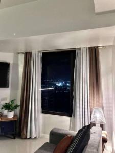 セブシティにあるGalleria Residences Towerのソファと大きな窓のあるリビングルーム