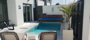 ein Schwimmbad in der Mitte eines Hauses mit Stühlen in der Unterkunft Casa Mariposa, 3 bedroom villa in Benijofar in Benijófar