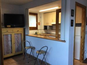 a kitchen with two stools and a counter with a television at Paso del Onso in Escarrilla