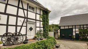 a white and black building with aoked wheel next to a door at Auszeit & Natur - ländliche Fachwerkhaushälfte in Nümbrecht
