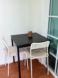a black table with two chairs and a plant on it at Good life home in U Tapao +16 photos