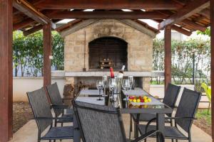 a patio with a table and chairs with a fireplace at Apartments Villa Mirela in Petrcane +109 photos