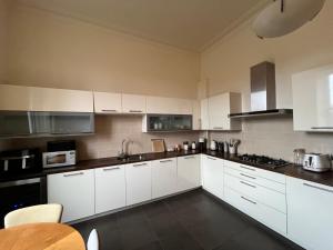 a white kitchen with white cabinets and a table at Quiet room in vibrant Bruntsfield with private parking in Edinburgh