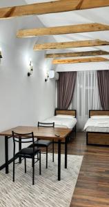 a room with two beds and a table and chairs at FlowerHouse in Karakol