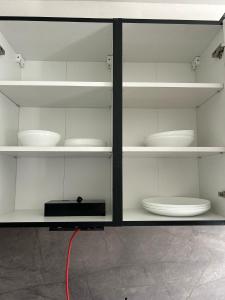 コシツェにあるYour home 11 with parkingのボウルや皿が置かれた白い棚のある部屋